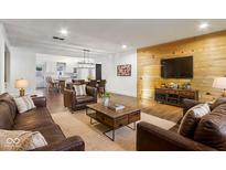 Open living room features hardwood floors, wood accent wall, recessed lighting, and an open kitchen at 3706 Candy Cane Dr, Indianapolis, IN 46227