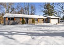 Gray brick ranch house with snow-covered yard, attached garage, and orange shutters at 4445 Cherry Ln, Indianapolis, IN 46228