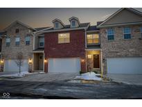 Brick front exterior of townhome with 2-car garage and snow-covered landscaping at 9725 Thorne Cliff Way # 101, Fishers, IN 46037