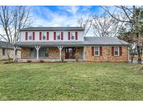 Charming two-story home featuring a welcoming front porch, brick facade, and well-maintained lawn at 7330 Tousley Dr, Indianapolis, IN 46256