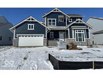 New construction navy two-story home featuring a white garage door and stone accents on a snowy lot at 770 Leila Mae Ln, Westfield, IN 46074