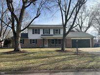 Charming two-story home featuring a brick and siding exterior, an attached garage, and a well-maintained front lawn at 6085 Manning Rd, Indianapolis, IN 46228
