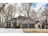 Charming two-story home with a brick facade, arched windows, and a two-car garage, surrounded by mature trees at 1242 Bitterwood Ct, Columbus, IN 47201