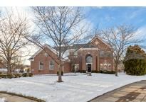 Brick two-story home with a snow-covered front yard and landscaping at 13886 Golden Saddle Ct, Carmel, IN 46032