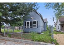 Charming blue house featuring a fenced yard, two windows, and mature trees at 2218 N Arsenal Ave, Indianapolis, IN 46218