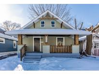 Charming craftsman bungalow with a covered porch and snow-covered lawn at 5009 E Michigan E St, Indianapolis, IN 46201