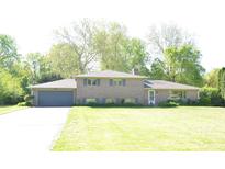 Charming brick home featuring a spacious front yard and attached two-car garage at 7027 Creekside Ln, Indianapolis, IN 46220