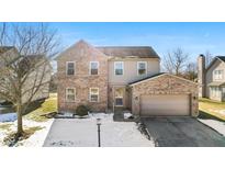 Two-story brick home with attached garage, snow-covered yard at 7609 Samuel Dr, Indianapolis, IN 46259