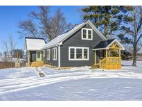 Gray farmhouse with a large front porch, sitting on a snowy lot at 11960 W S R 42, Martinsville, IN 46151