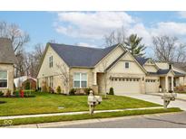 Beige two-story house with a three-car garage and manicured lawn at 1476 Hideaway Cir, Brownsburg, IN 46112