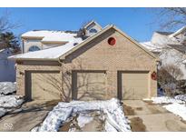 Brick front exterior of charming home with three-car garage and snow-covered driveway at 3740 Magenta Ln # 5, Indianapolis, IN 46214