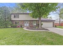 Charming two-story brick home with a well-manicured lawn and mature trees at 409 Lansdowne Rd, Indianapolis, IN 46234