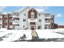 Brick and gray condo building with snow-covered parking lot at 6239 Amber Creek Ln # 104, Indianapolis, IN 46237
