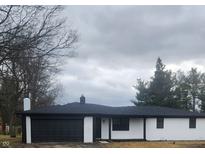 Charming exterior of a brick home with a black garage door and mature trees at 6805 E County Road 100 S, Avon, IN 46123