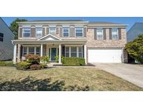 Two-story brick home with a welcoming front porch and attached two car garage at 10406 Corning Way, Fishers, IN 46038