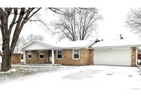Brick ranch home with attached garage, snowy front yard, and mature trees at 2006 E 44Th St, Anderson, IN 46013