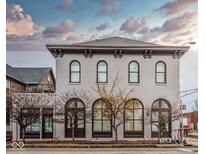 Charming building featuring a light brick facade, arched windows, and classic architectural details under a cloudy sky at 304 N College Ave # Apt B, Indianapolis, IN 46202