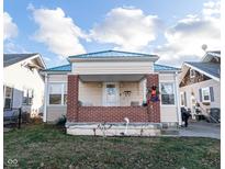 Cute bungalow with a green metal roof, brick porch and a well-manicured lawn at 4815 English Ave, Indianapolis, IN 46201