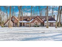 Brick home with snow-covered lawn, nestled among tall trees at 7425 Cherryhill Dr, Indianapolis, IN 46254