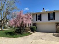 Charming two-story home with a beautifully landscaped front yard and attached garage on a sunny day at 7629 Farm View W Cir, Indianapolis, IN 46256
