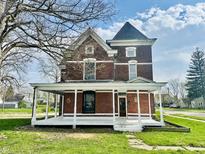 Charming two-story brick home featuring a welcoming wrap-around porch and detailed architectural accents at 503 S Harrison St, Alexandria, IN 46001