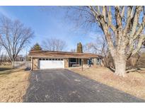 Ranch-style home featuring a charming brick exterior, attached garage, and well-manicured lawn in a tranquil neighborhood at 7828 N Sherman Dr, Indianapolis, IN 46240