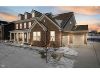 Two-story brick home with a three-car garage and a snow-covered front yard at 12346 Palmetto Bay St, Fishers, IN 46037