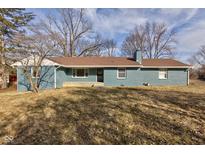 Ranch-style home with brown roof, blue brick, chimney, and a yard with mature trees and dormant grass at 4660 42Nd St, Indianapolis, IN 46226