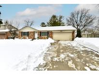 Brick ranch house with attached garage, snow-covered yard, and driveway at 7339 Mcfarland Rd, Indianapolis, IN 46227