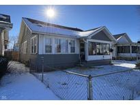 Gray house with white trim, sun porch, and chain link fence in snowy yard at 1713 W 11Th St, Muncie, IN 47302