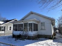 White house with screened porch and snowy yard at 1717 W 11Th St, Muncie, IN 47302