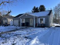 Gray ranch house with a snow-covered yard and attached garage at 1801 E 23Rd St, Muncie, IN 47302