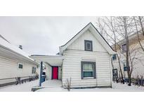 Charming white house with red door, covered porch, and snowy yard at 1819 Southeastern Ave, Indianapolis, IN 46201