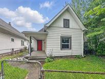 Charming home with a red front door and light colored siding surrounded by a metal fence and some plants at 1819 Southeastern Ave, Indianapolis, IN 46201