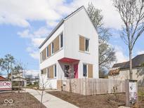 Charming two-story home with white siding, contrasting trim, pink door, and a cute picket fence at 220 N Beville Ave, Indianapolis, IN 46201