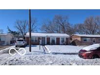 Ranch-style home with a snow-covered lawn and driveway at 2714 Baltimore Ave, Indianapolis, IN 46218
