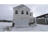 Two-story home featuring a two-car garage, white siding, and black roof in a snowy neighborhood at 1845 James Pierce Dr, Shelbyville, IN 46176