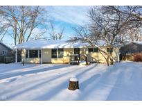 Ranch home with snow-covered yard, features a front entrance and attached deck at 2250 N Pasadena St, Indianapolis, IN 46219