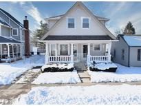 Snow covered exterior of a charming two story home with a wrap around porch at 238 S 5Th Ave, Beech Grove, IN 46107