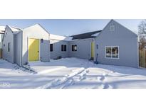 Newly renovated home with gray siding and a bright yellow door, nestled on a snow-covered lot at 2833 Hervey St, Indianapolis, IN 46203