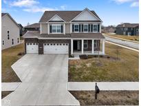 Inviting two-story home with a three-car garage, manicured lawn, and charming front porch at 4201 Risen Star Way, Bargersville, IN 46106