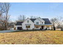 Two-story white farmhouse with gray roof, landscaping, and attached garage at 5119 E 71St St, Indianapolis, IN 46220