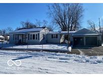 Ranch home with snow-covered yard, attached garage, and fenced-in front yard at 5721 Shimer Ave, Indianapolis, IN 46219