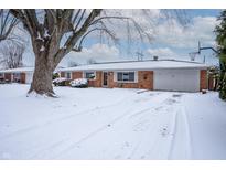 Brick ranch home with snow-covered yard and basketball hoop at 1707 E 45Th St, Anderson, IN 46013