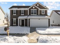 Two-story house with brown siding, white garage door, and snowy front yard at 10115 Redwood Peak Ln, Indianapolis, IN 46259