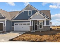 Charming blue home featuring stone accents, a two-car garage, and impeccable architectural details at 16673 Cattle Hollow Ln, Noblesville, IN 46060