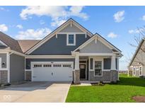 Charming single Gathering home featuring a two-car garage, manicured lawn and stone-accented facade at 16673 Cattle Hollow Ln, Noblesville, IN 46060