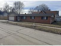 Charming brick home featuring an attached garage and well-maintained front yard at 1801 W Morris St, Indianapolis, IN 46221
