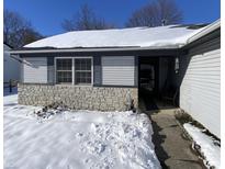 Ranch home with gray accents and stone details. Snow covered yard at 3332 Lauren Dr, Indianapolis, IN 46235