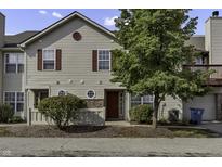 Tan two-story townhouse with red door and landscaping at 4652 Kimmeridge Ln, Indianapolis, IN 46254